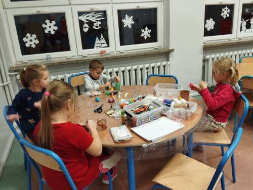 Dzieci podczas zajęć siedzą przy stolikach.