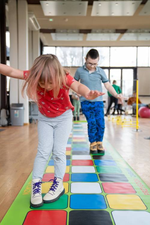 Dzieci podczas zabawy – skoki na kolorowych kwadratach.