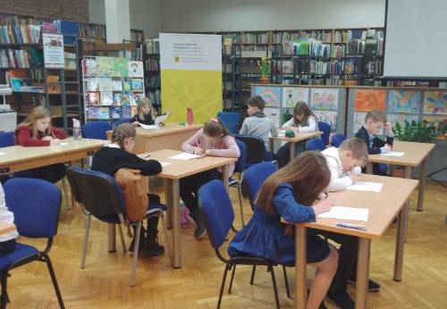 Uczniowie podczas pisania testu w bibliotece.