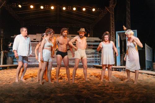 Aktorzy w piasku na scenie.