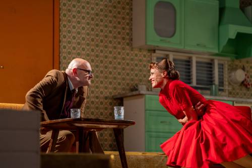 Mężczyzna w garniturze oraz kobieta w czerwonej sukience na scenie.