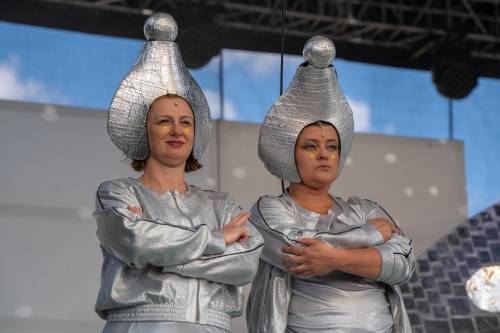 Dwie kobiety w srebrnych, kosmicznych strojach z dziwnymi nakryciami głowy.