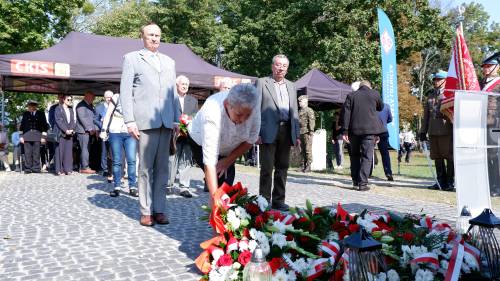 Składanie kwiatów pod pomnikiem przez gości.