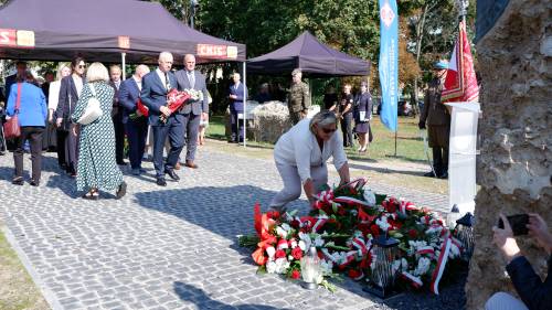 Składanie kwiatów pod pomnikiem przez gości.