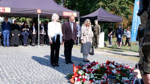 Składanie kwiatów pod pomnikiem przez gości.