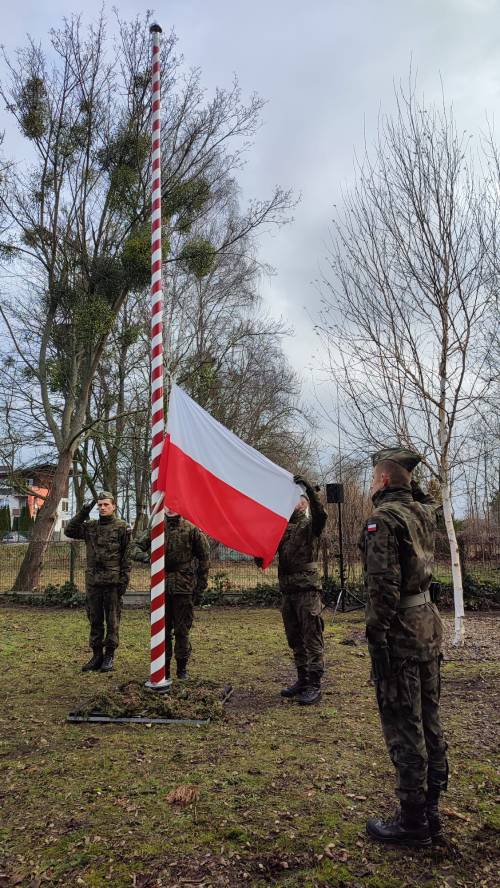 Żołnierze wciągają flagę na maszt.