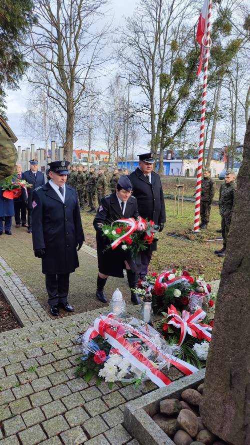 Goście uroczystości składają kwiaty pod pomnikiem przy ul. Powstańców Warszawy – mundurowi.