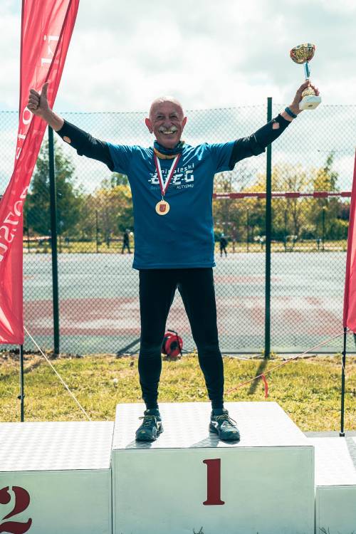 Najstarszy uczestnik z pucharem stoi na podium.