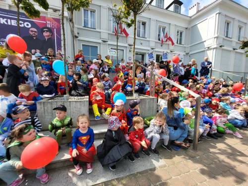 Dzieci w strojach superbohaterów siedzą na schodach Urzędu Miasta.