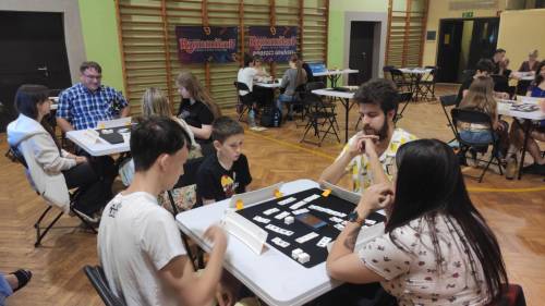 Rozgrywki Rummikub, zawodnicy siedzą przy stolikach