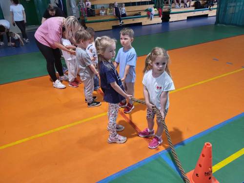 Dzieci w hali sportowej trzymają linę do przeciągania