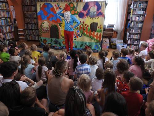 Przedstawienie w bibliotece, dzieci siedzą na podłodze, przed nimi stoi Papa Smerf