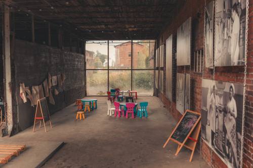 Kolorowe dziecięce krzesełka i stoliki w industrialnej przestrzeni cukrowni.