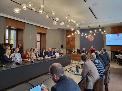 Radni Rady Miasta przy stolach. Szeroki kadr.