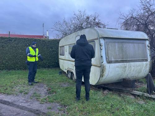 Dwie postacie stojące przy przyczepie kempingowej