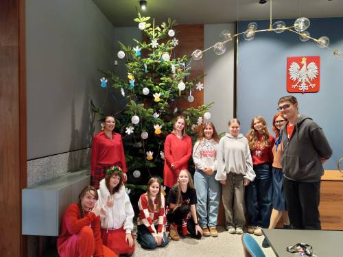 Dzieci i młodzież z opiekunami przy choince