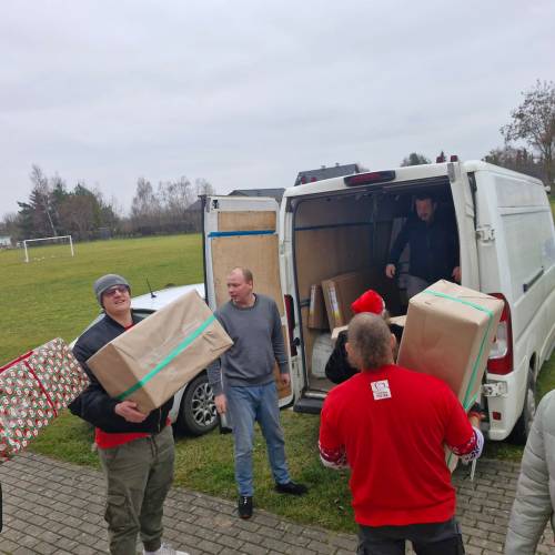 Grupa wolontariuszy pakuje paczki na samochód