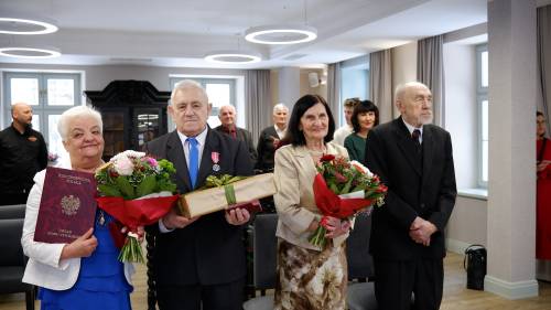 Dwie pary jubilatów z kwiatami i prezentami