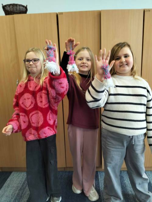 Trzy uczennice z samodzielnie zrobionymi skrzatami z włóczki