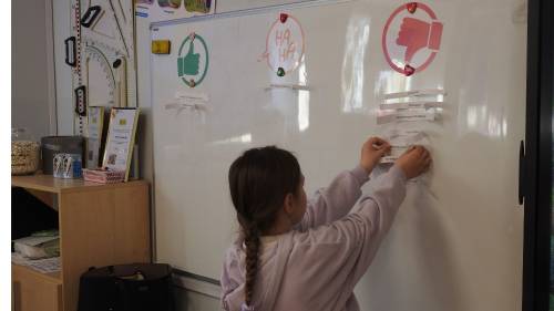 Dziewczynka przypina karteczkę do tablicy