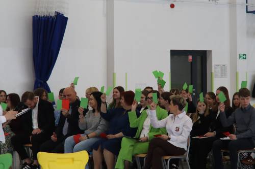 Uczestnicy sejmiku podnoszą ręce z zielonymi i czerwonymi kartkami