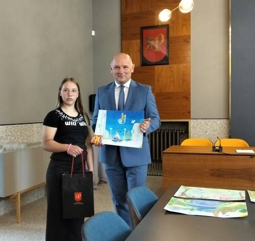 Jedna z laureatek z zastępcą burmistrza trzymającym pracę