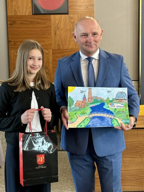 Nagrodzona uczennica z zastępcą burmistrza, który trzyma w rękach jej pracę