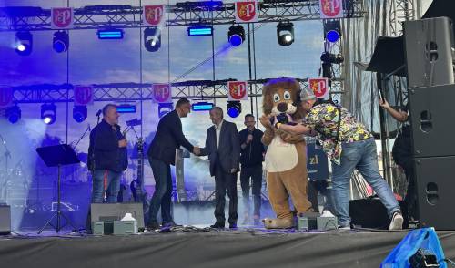 Burmistrz Pruszcza ściska rękę starszemu panu na scenie, obok lewe maskotka