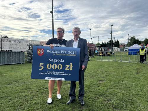 Kobieta i starszy mężczyzna z planszą z napisem Nagroda