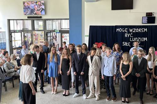 Grupa uczniów stoi pod napisem Mogę wzorem być ludziom