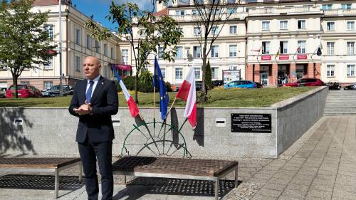 Starosta gdański stoi przed flagami i tablicą pamiątkową