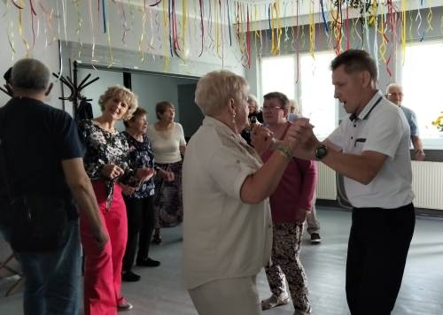 Grupa seniorów tańczy na parkiecie