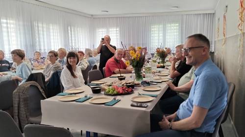 Widok na salę z siedzącymi seniorami i gośćmi
