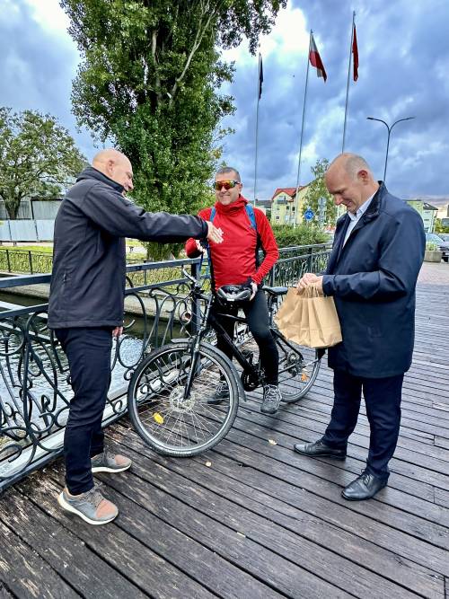 Zastępca burmistrza Pruszcza Gdańskiego i starosta gdański wręczają rowerzyście gadźety